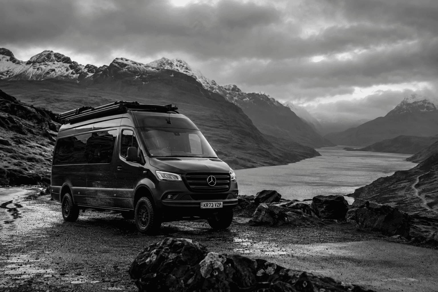 A camper van parked beside a Scottish loch under a moody sky